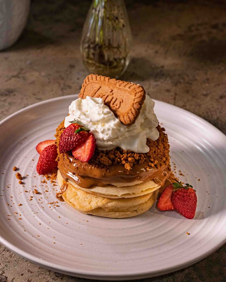 Our Biscoff Pancakes with strawberries, cream and a Lotus biscuit, photographed at First Fruits Coffee